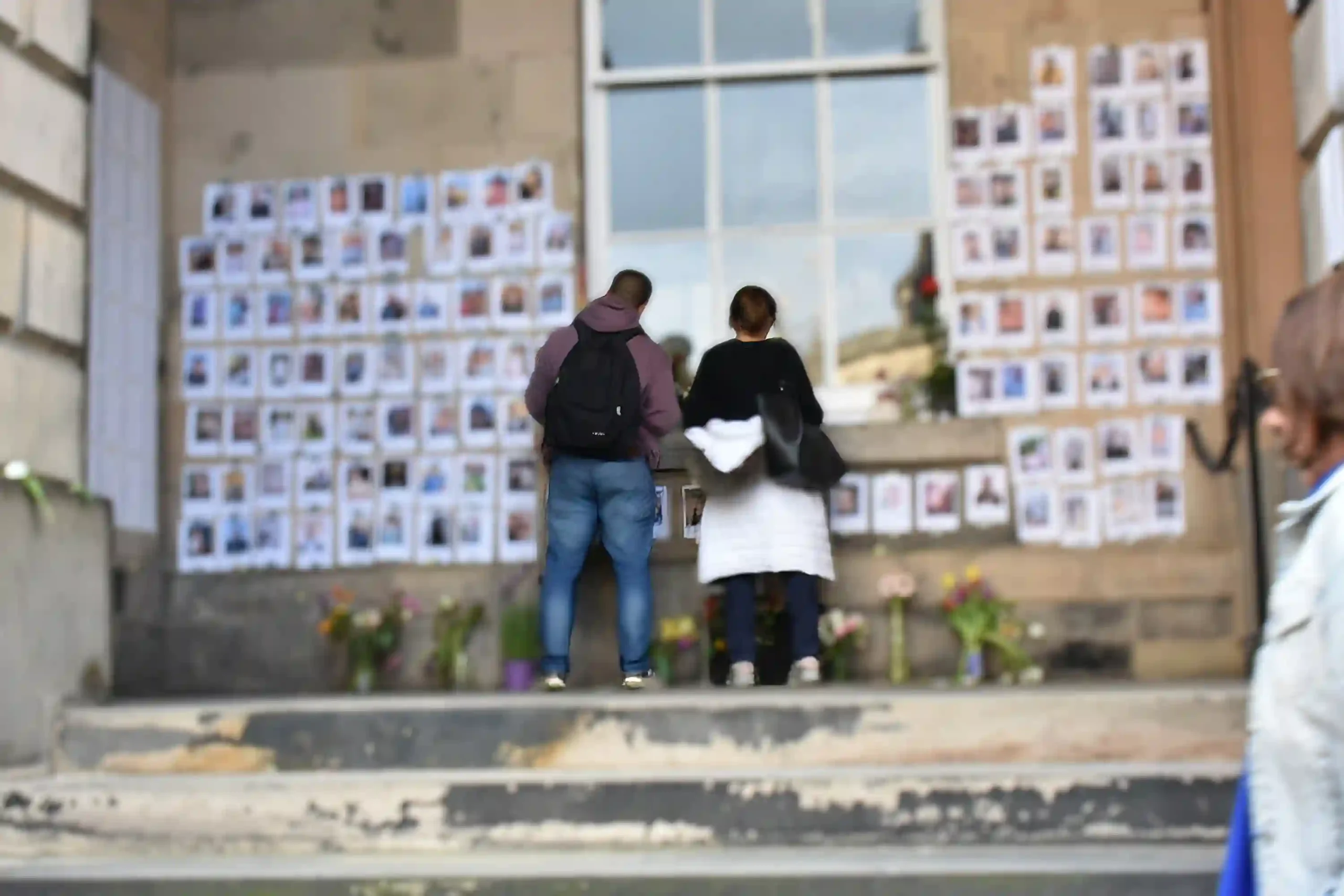 People standing reading names on pictures of people killed in Israeli operations in Gaza at the University of Edinburgh memorial